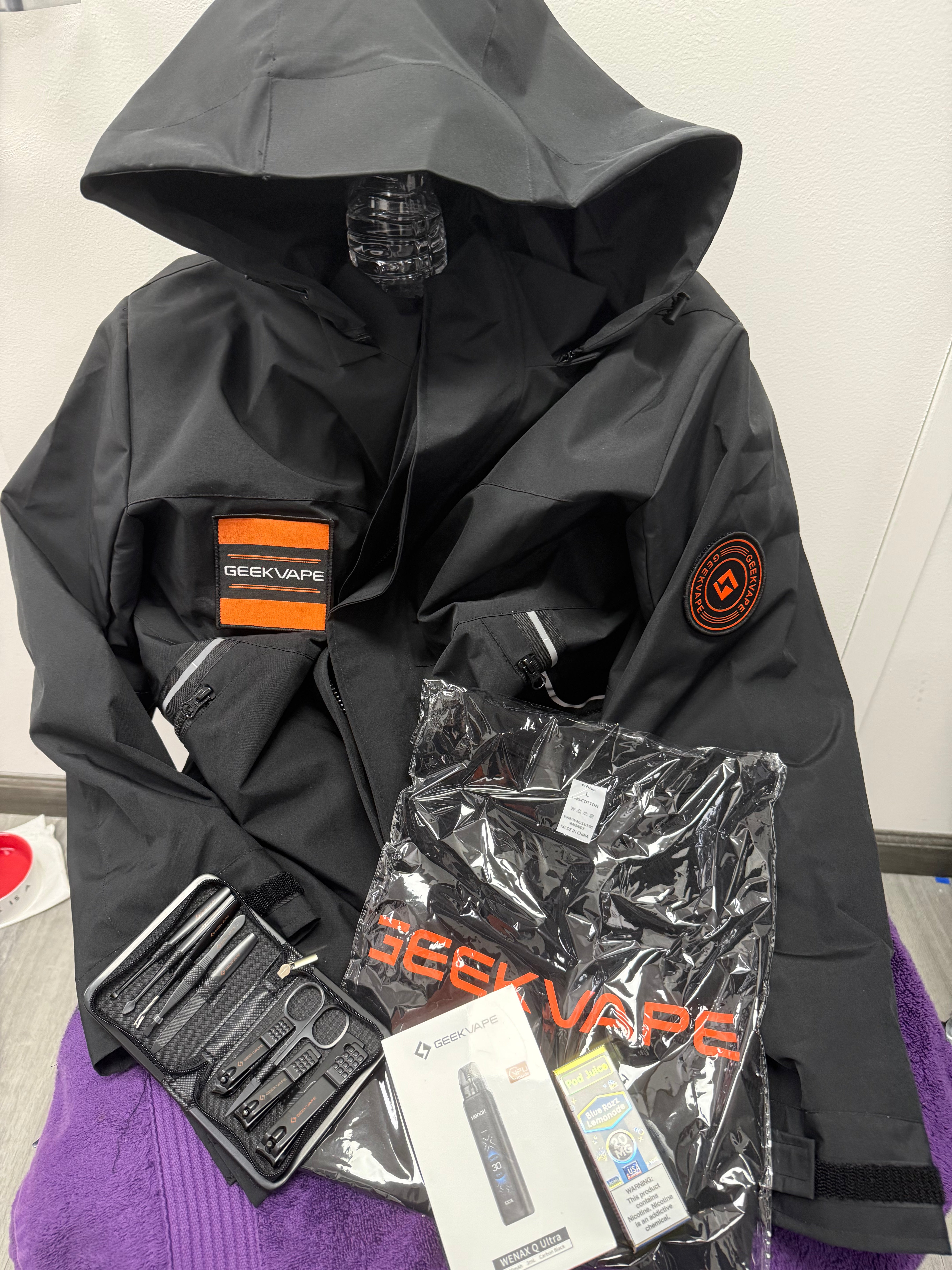 Black hooded jacket with Geekvape branding and accessories on a white background